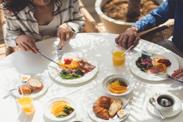 写真：オムレツやパン、フルーツなどのこだわりの朝食を楽しむカップルの様子