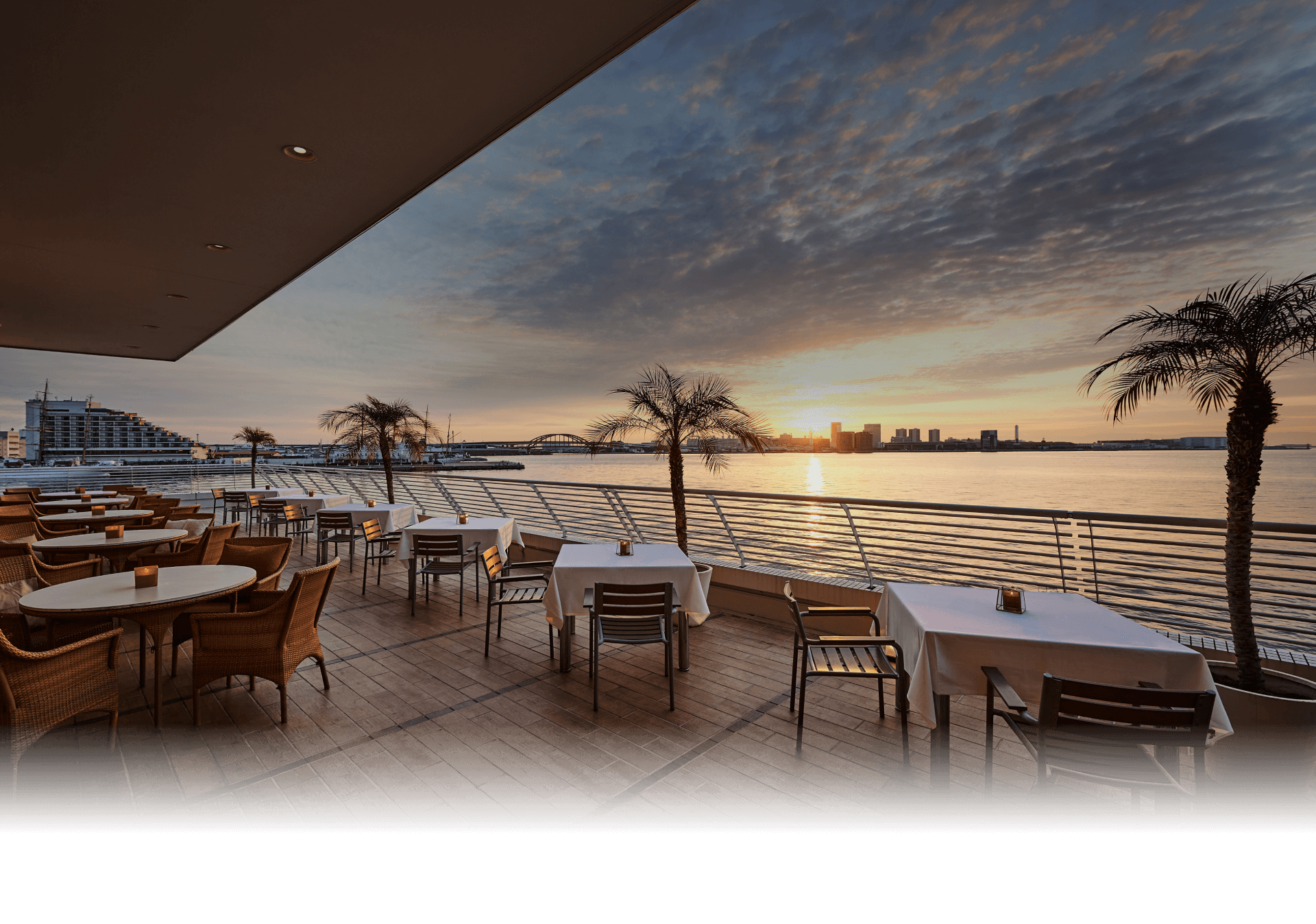 写真：レストラン「テラス＆ダイニング　オールフラッグ」のオープンテラス席と夕方の海