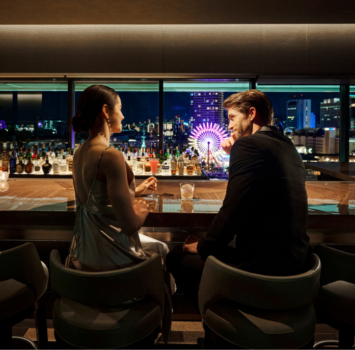 写真：バー VIEW BARのカウンター席でお酒を飲んでいるカップル