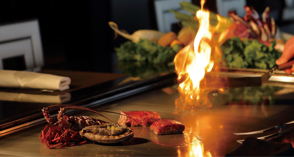写真：シェフが神戸ビーフ、あわび、伊勢海老などを鉄板焼で調理する様子